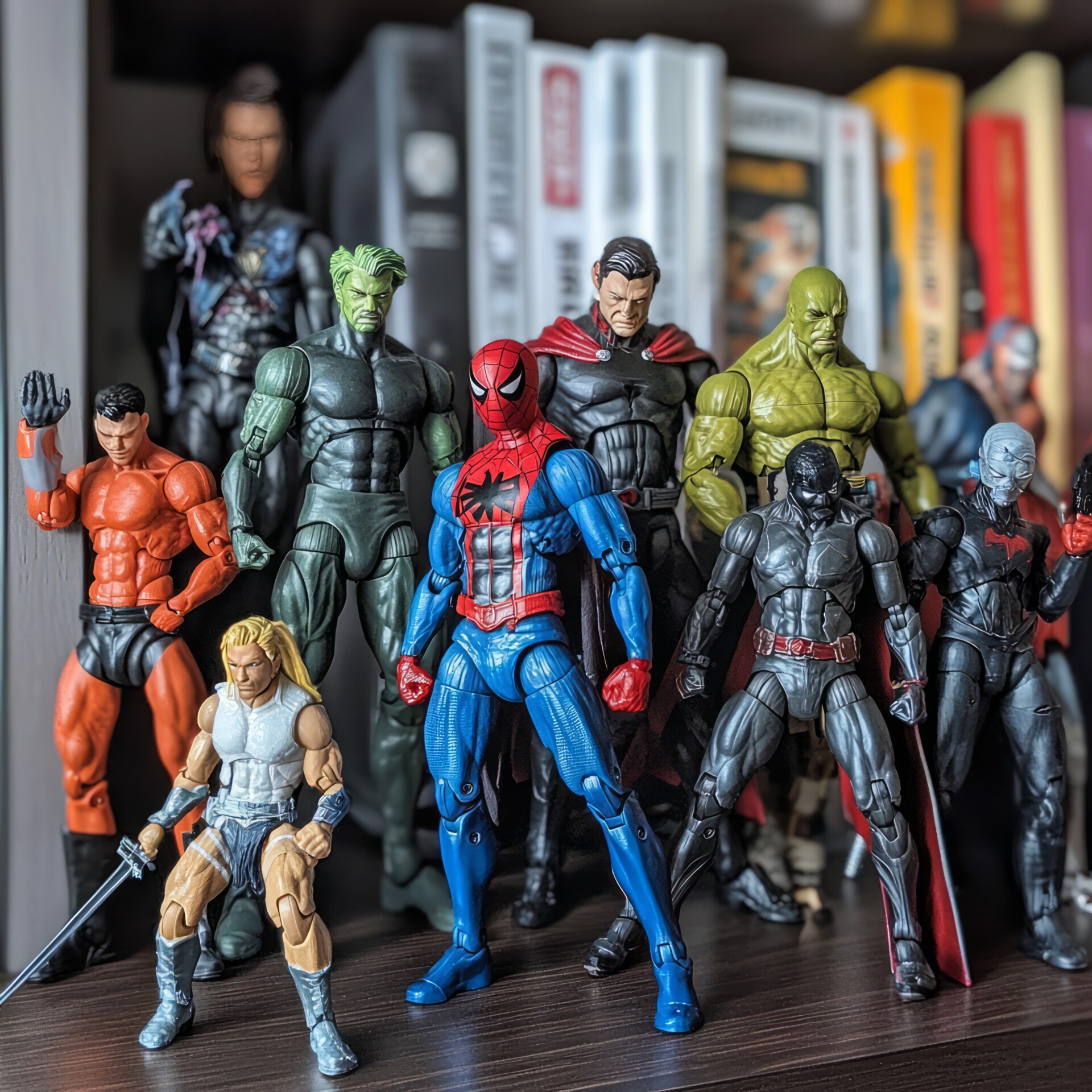 a collection of superhero action figures stand in front of a bookshelf.